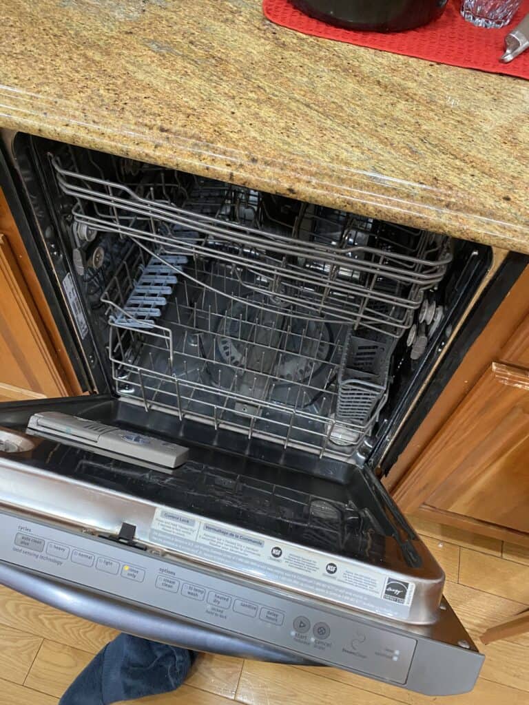 Open built-in dishwasher showing the interior racks