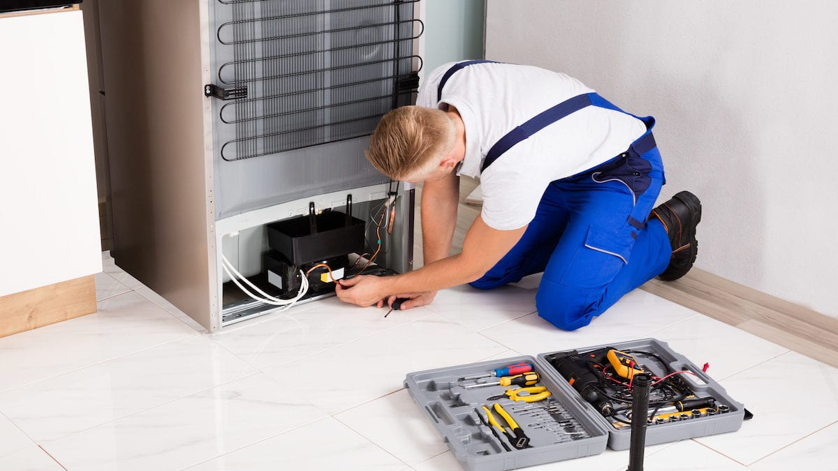 Technician inspecting the back of a refrigerator