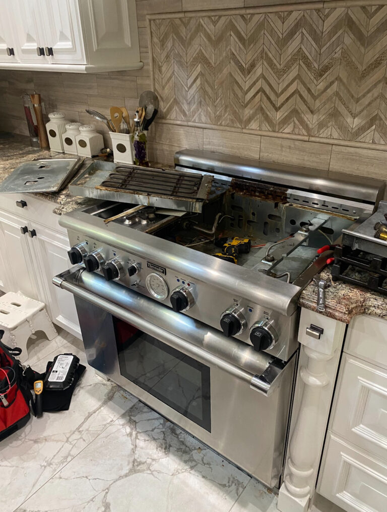 Stainless steel range with cooktop panels removed and tools beside it