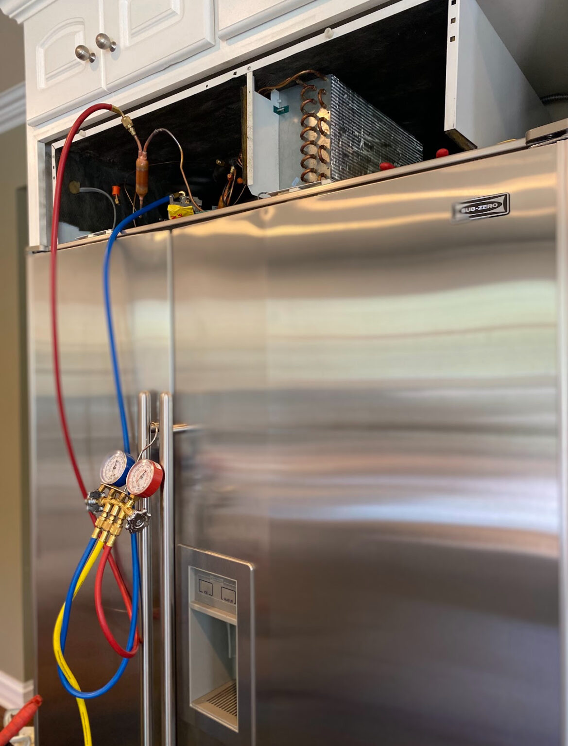 Sub-Zero refrigerator with the upper service compartment open and diagnostic gauges attached